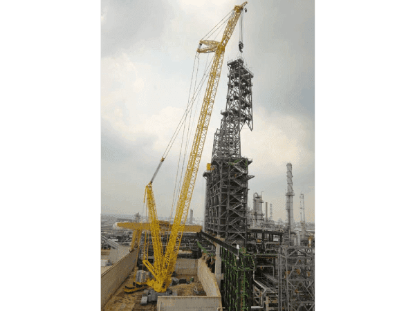 A crane is in front of an oil refinery.