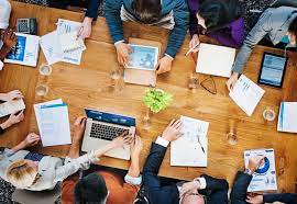 A group of people sitting around a table with papers.